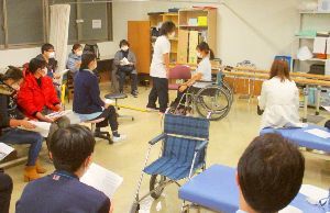 リハビリ職員の指導を聴く看護補助者